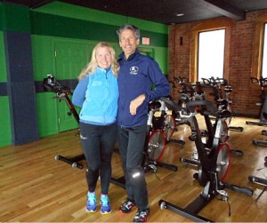In their new space with bright green accent wall and exposed brick, Kent and Shiobbean Lemme pose with their exercise bikes