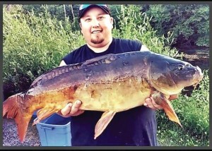 Big smiling fisherman proudly holds up his huge bowfin on the Onota Lakeside