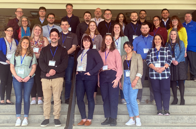 A large group of people - the 2023 class of the Berkshire Leadership Program - stand on steps smiling for the camera.