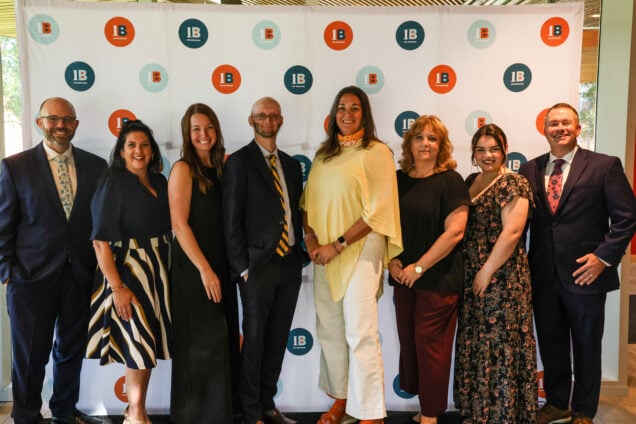 The 1berkshire staff stand together in front of a photo backdrop