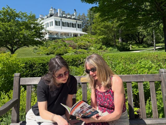 Two women read the Guide to the Berkshires in the summer gardens at The Mount